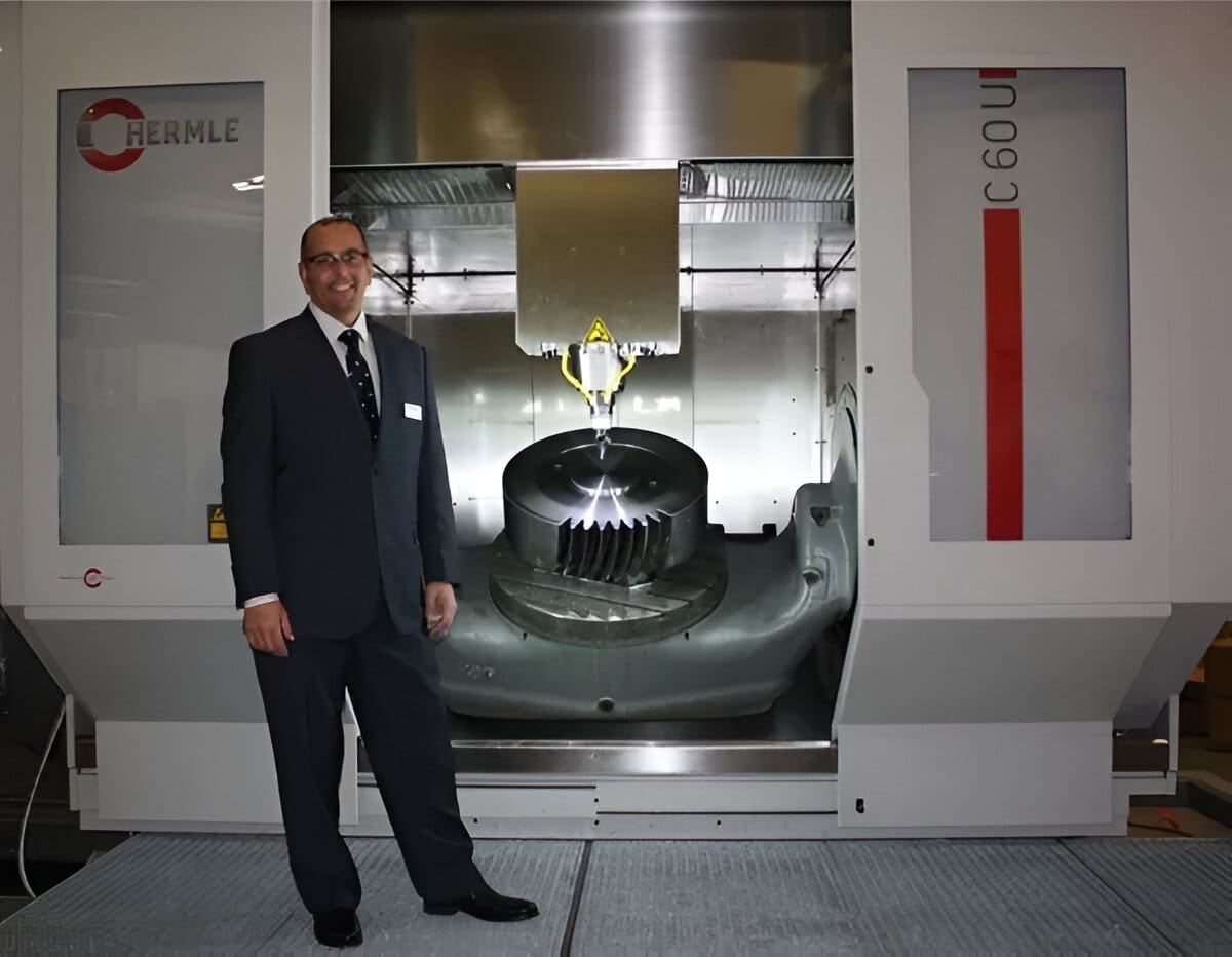 A man in a suit standing next to an industrial machine.